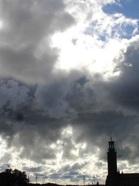 Clouds above the city hall. The dark dot near the center left is probably a lens flare.
