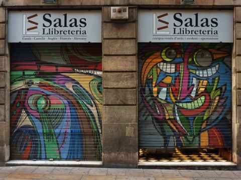 Example of art on the roller shutters of a store. On the right shutter a pair of something that looks like the "Happy Fish" by Pez can be seen making up the eyes of the face.